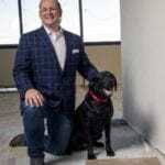 AmeriVet CEO Thomas Thill, pictured kneeling with his dog Ace in an office under construction