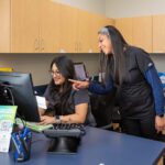 two team members smiling and pointing at computer screen