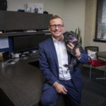 AmeriVet COO Chris Flowers, pictured sitting on his desk in his office holding a puppy