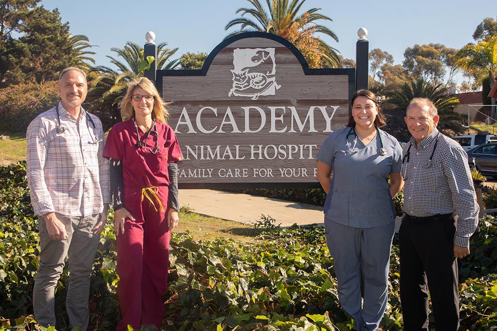 veterinary team standing in front of animal hospital sign