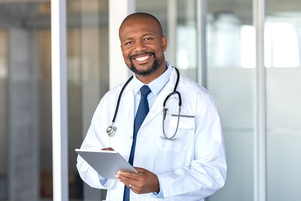 doctor happily standing in front of practice and holding a tablet
