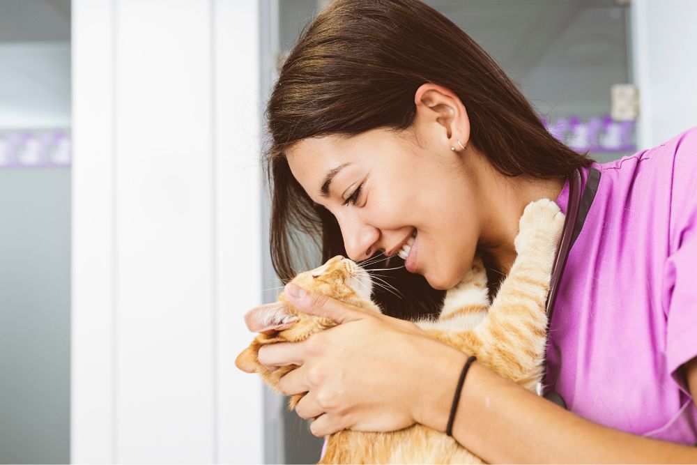 veterinarian blissfully hugging a small orange cat