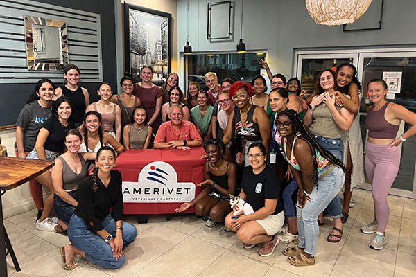 large group of vet students posing around an AmeriVet table