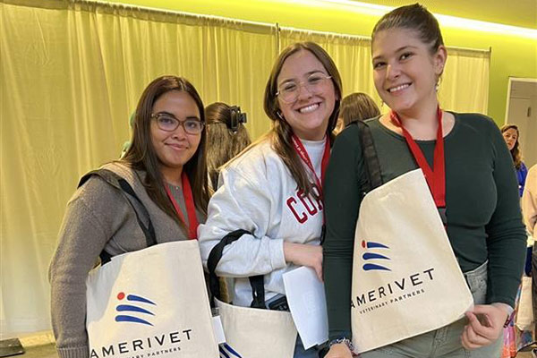 three veterinary students smiling and holding AmeriVet tote bags